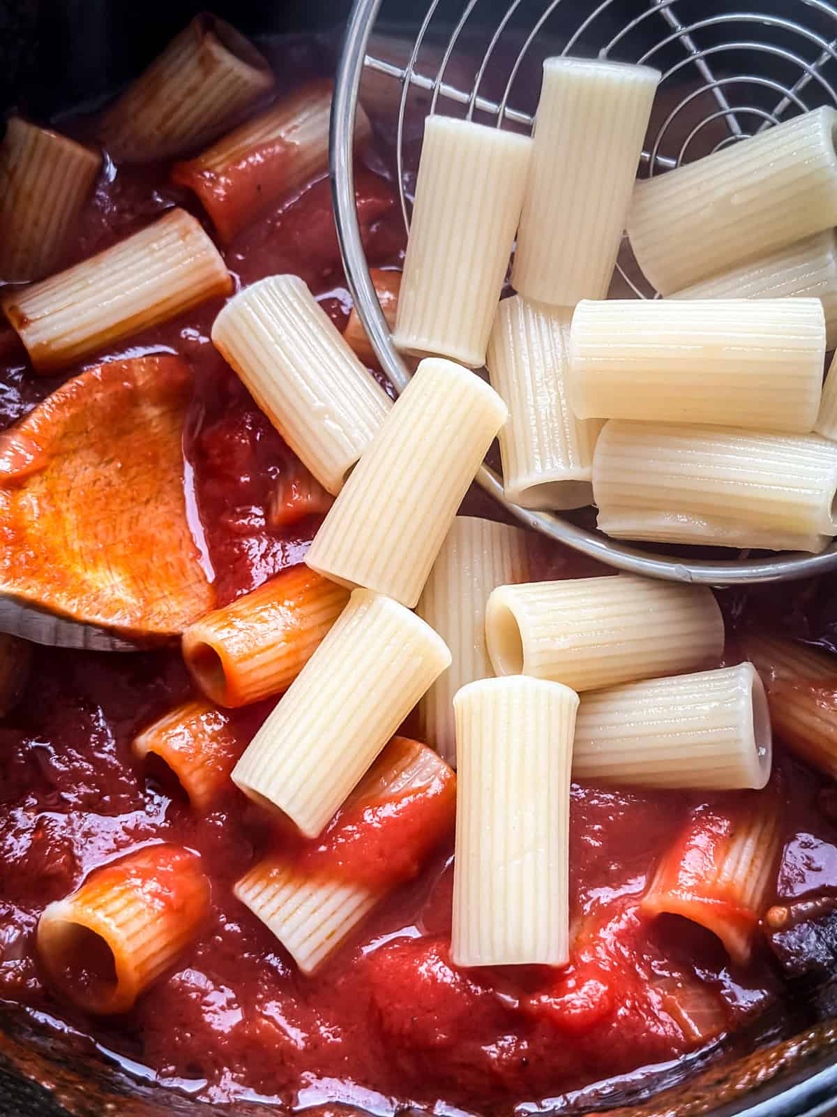 Close overhead view of rigatoni tossed in spicy tomato sauce with pancetta
