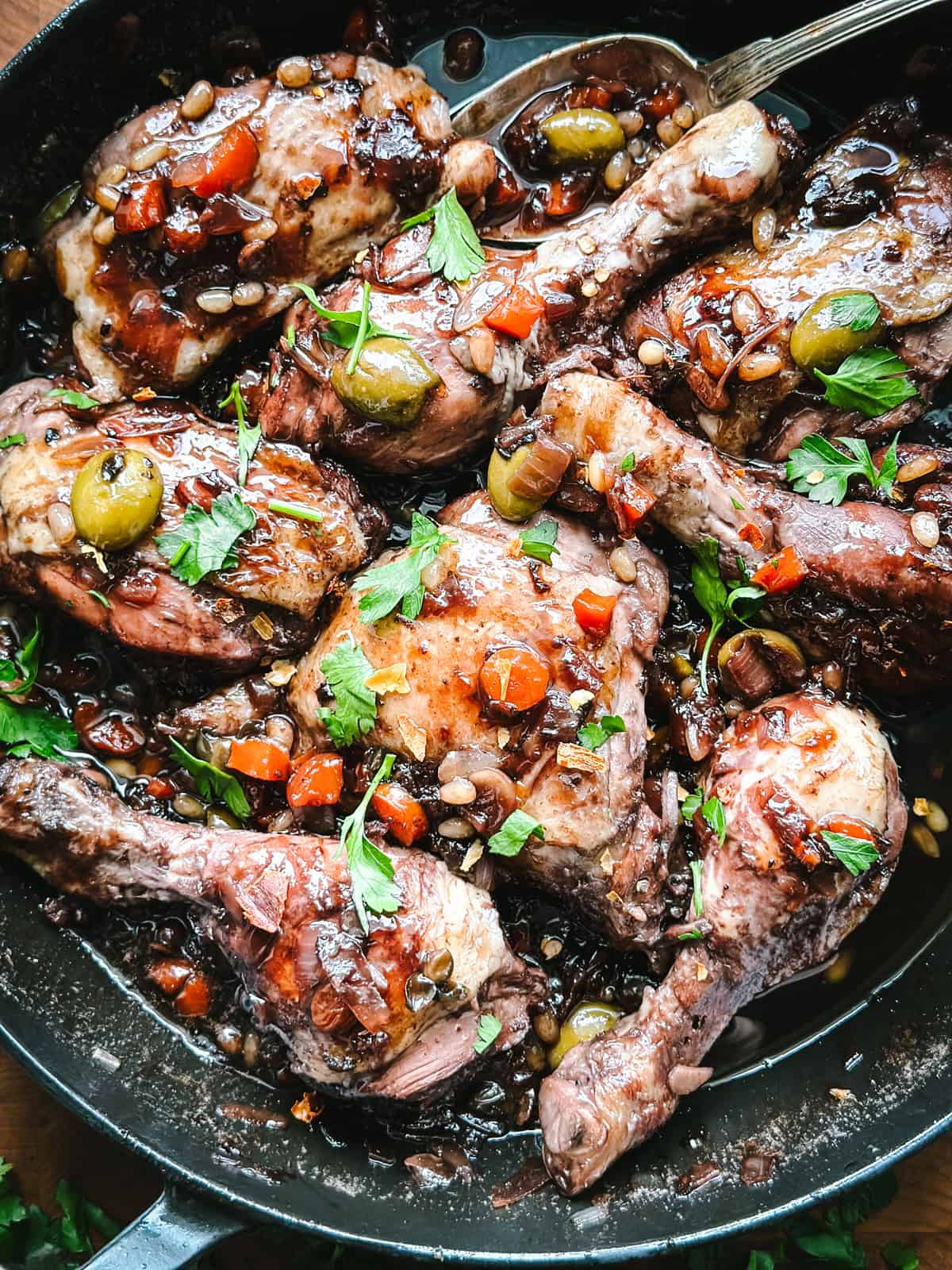 Close-up of Sicilian chicken glazed in dark vin cotto sauce with pine nuts and green olives.