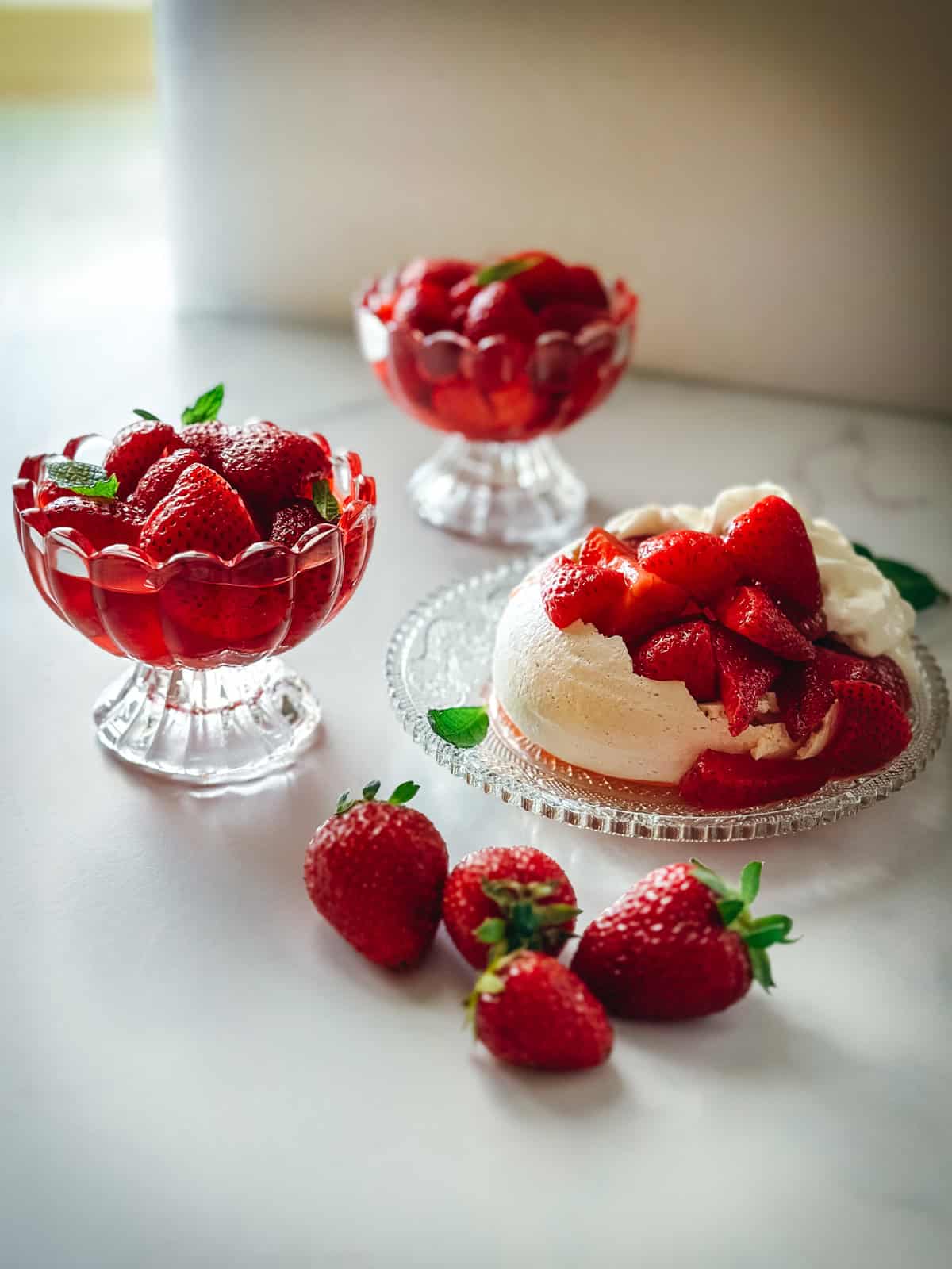 Macerated strawberries served in glass coupes and spooned over a pavlova