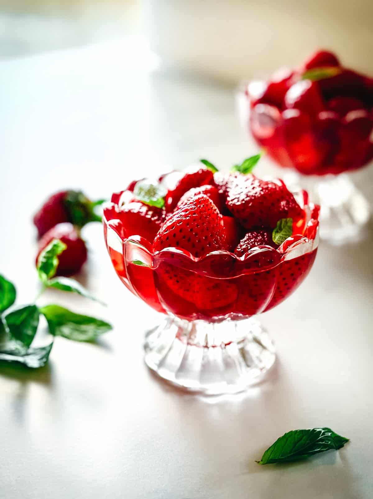 Macerated strawberries in glossy syrup served in a vintage glass coupe