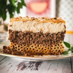 Side view of a pastitsio slice showing three layers: tubular pasta, beef ragù, and golden béchamel