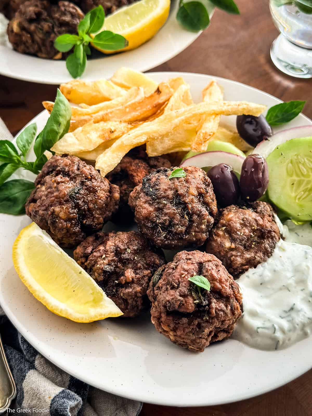 Traditional Greek meatballs with a lemon wedge, fresh oregano and creamy tzatziki dipping sauce.