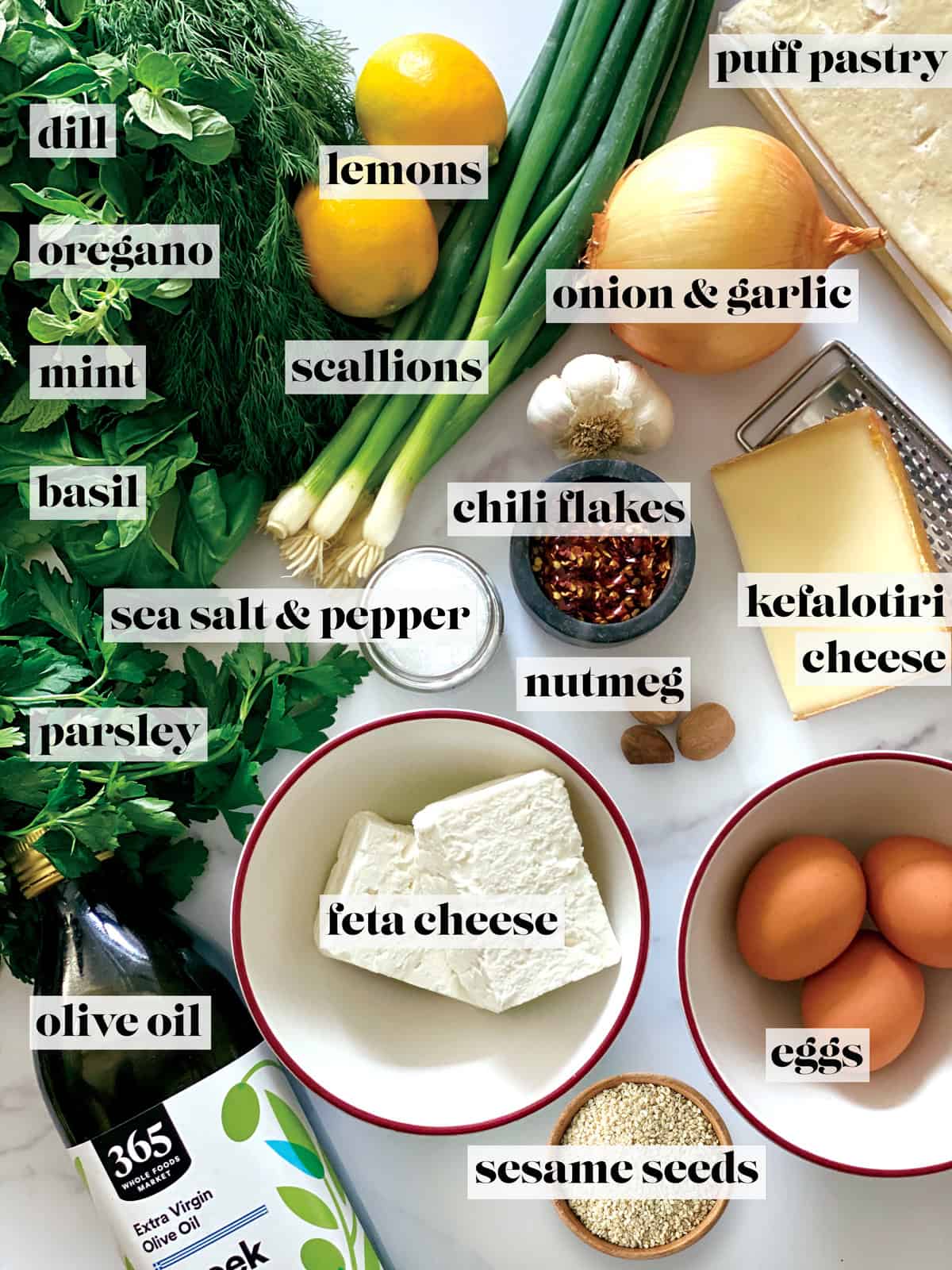 Labeled ingredients for hortopita — greens, herbs, feta, eggs, lemons, olive oil and puff pastry.