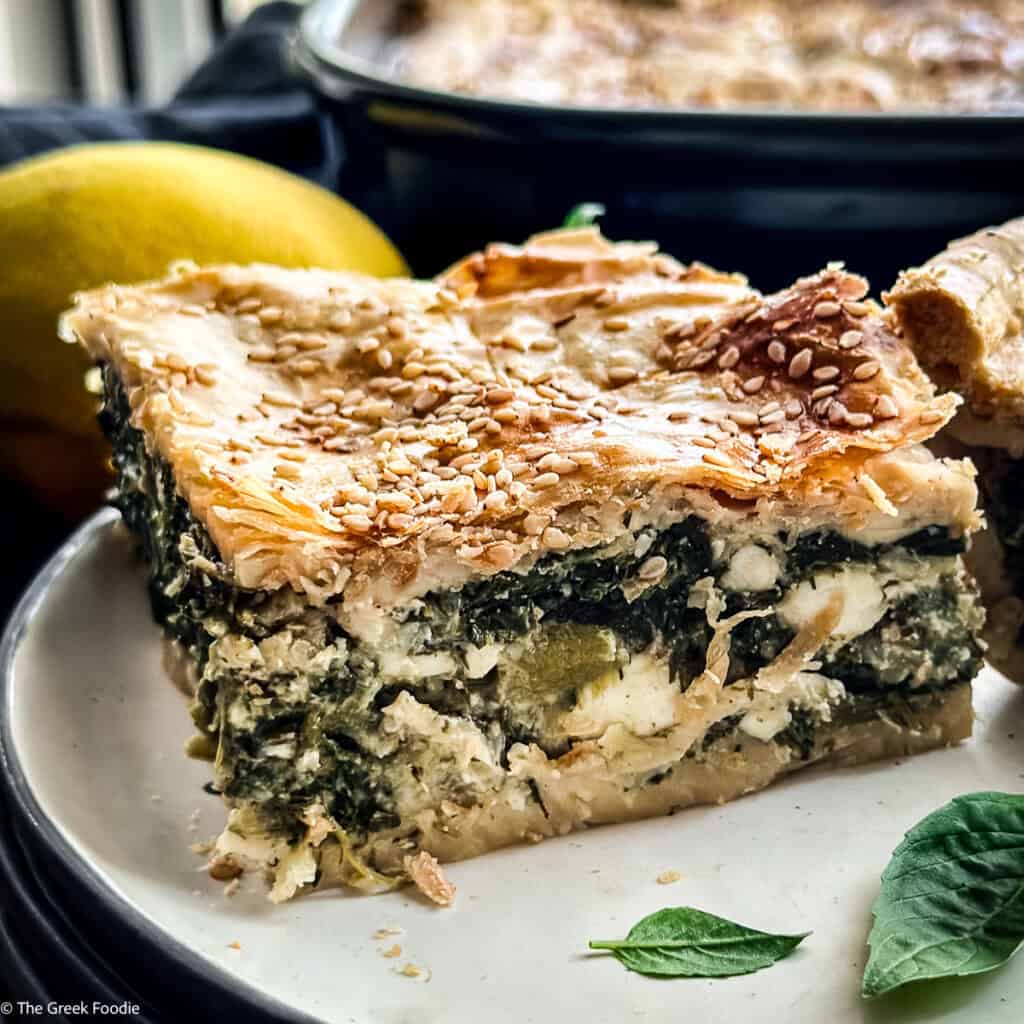 Close-up of a hortopita square showing the greens and feta filling between crisp golden pastry.