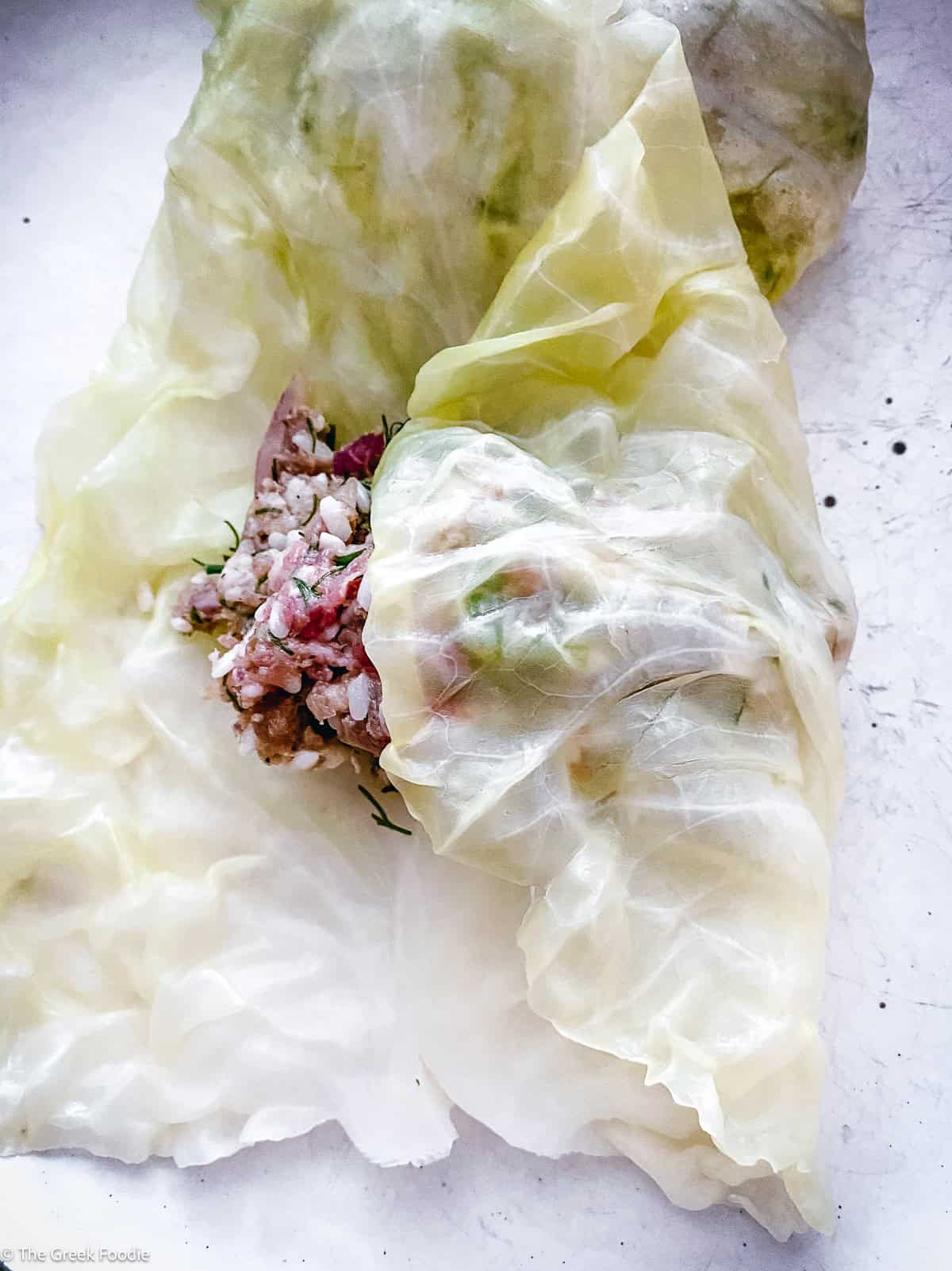 Spoonful of meat and rice filling placed on a blanched cabbage leaf ready to roll