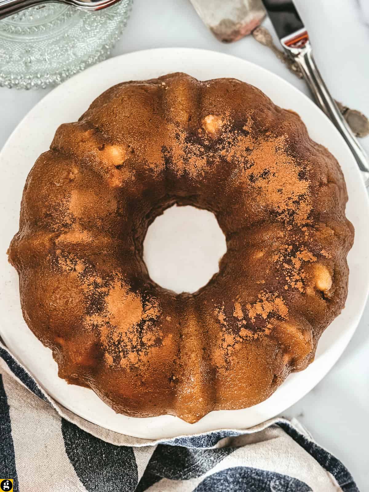 Greek halva, a semolina and olive oil dessert shaped in a bundt pan, dusted with cinnamon on a white platter, seen from above