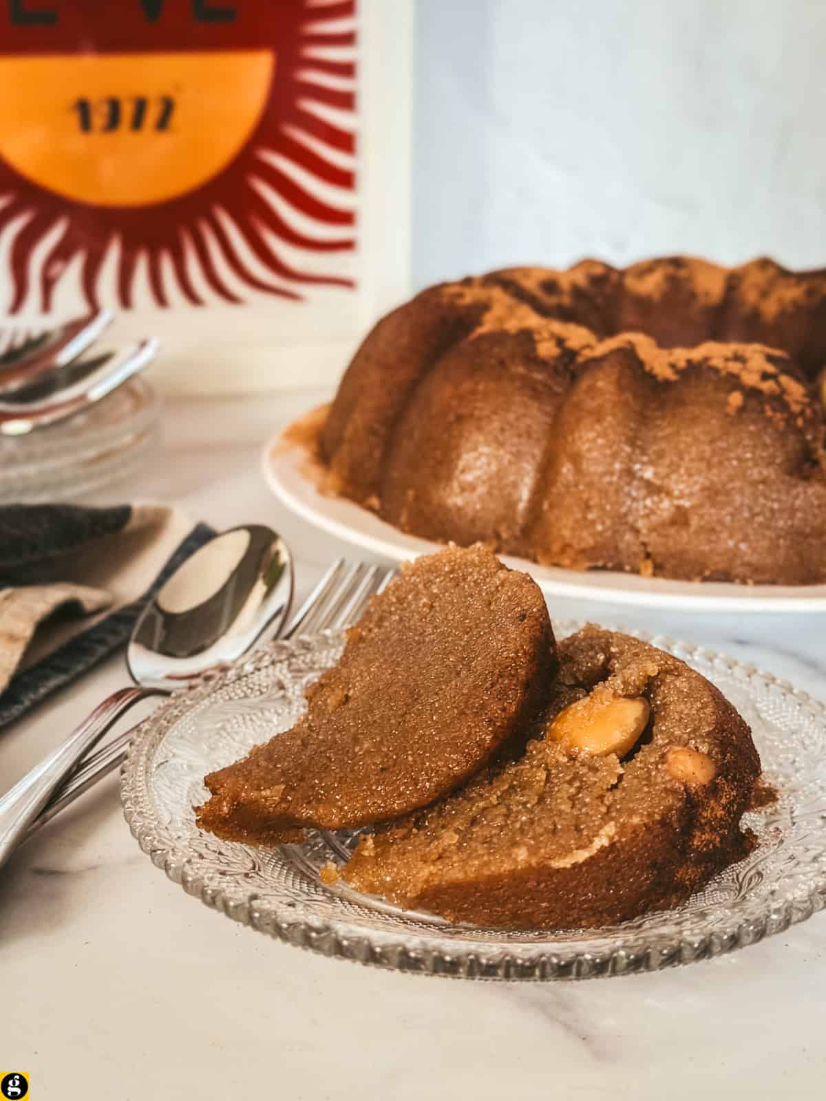 Two slices of Greek semolina halva on a glass plate, one showing a whole almond inside