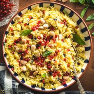 Overhead view of Greek saffron rice pilafi in a blue and white striped bowl with a serving spoon.