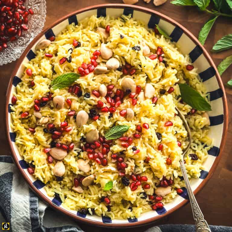 Overhead view of Greek saffron rice pilafi in a blue and white striped bowl with a serving spoon.