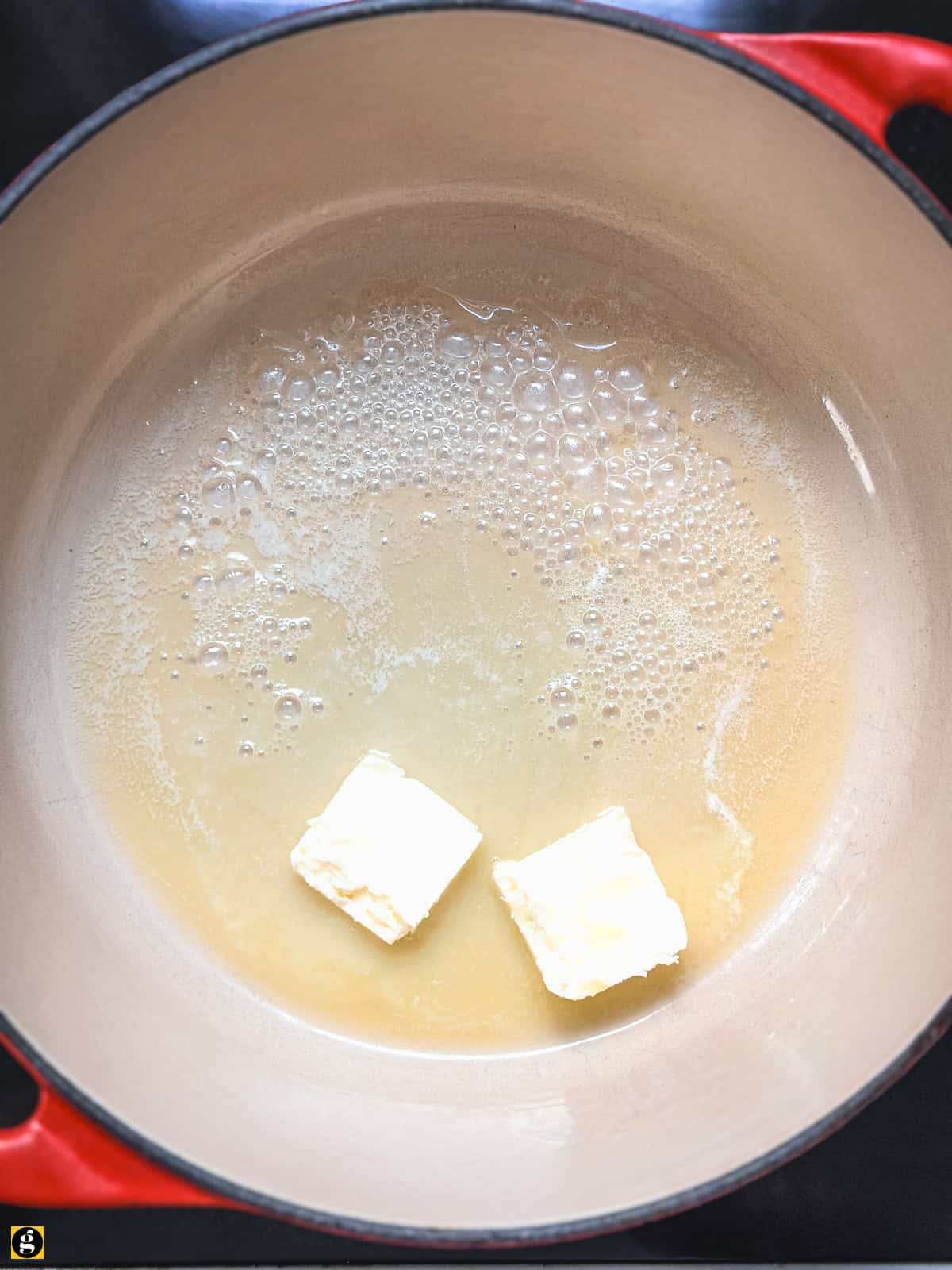 Butter melting in a red Dutch oven for Greek rice pilaf.