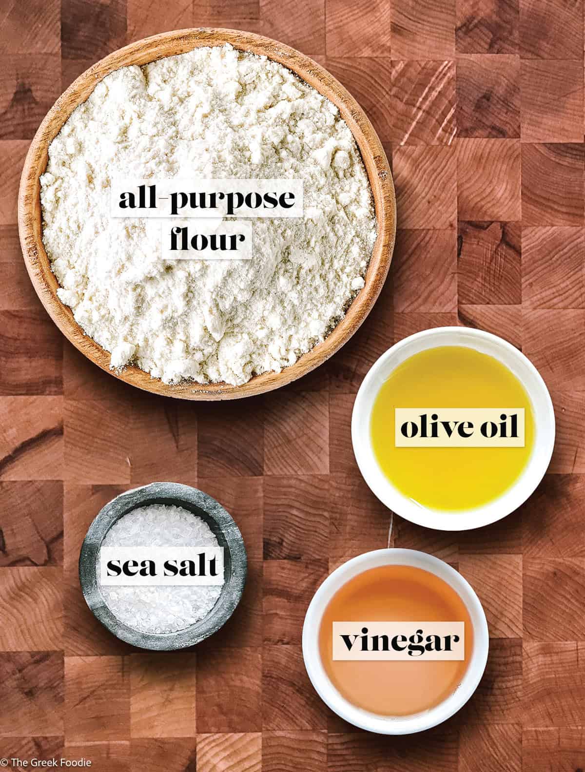 Ingredients for homemade phyllo dough on a wooden board: all-purpose flour, olive oil, sea salt and vinegar.
