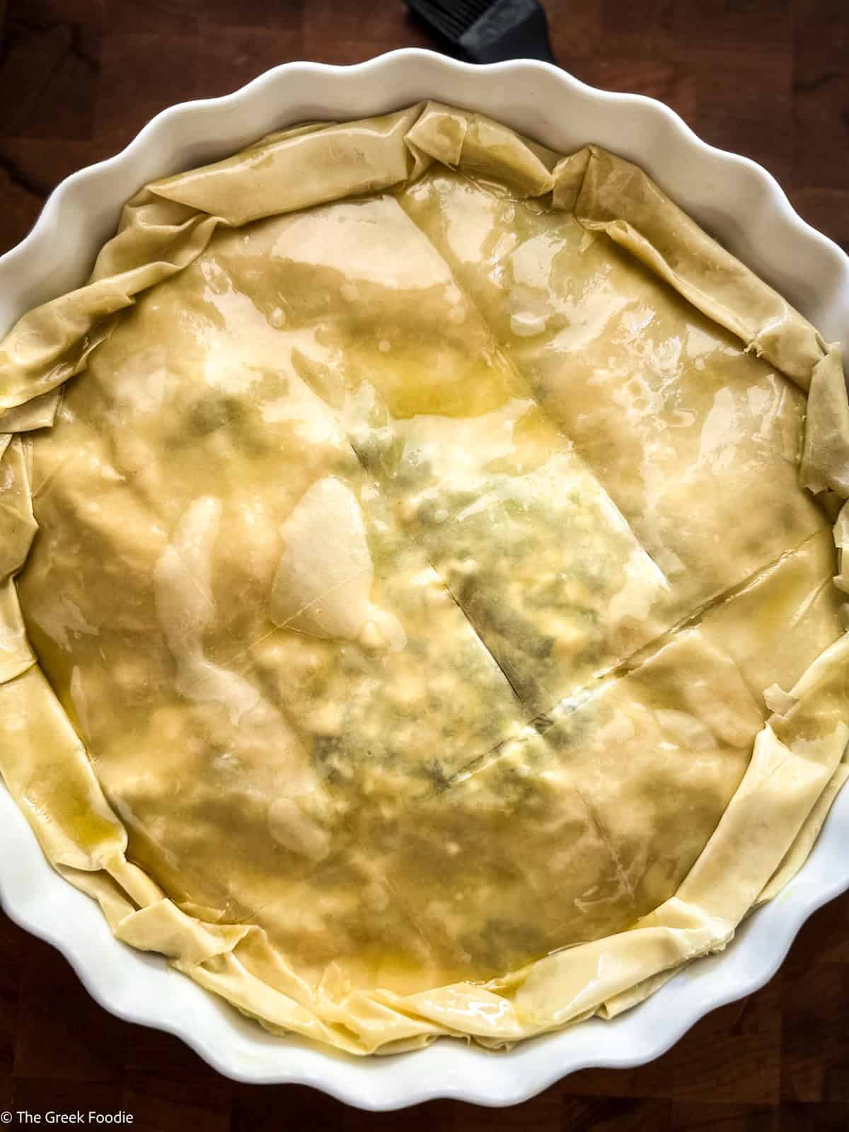 Assembled spanakopita scored into portions before baking.