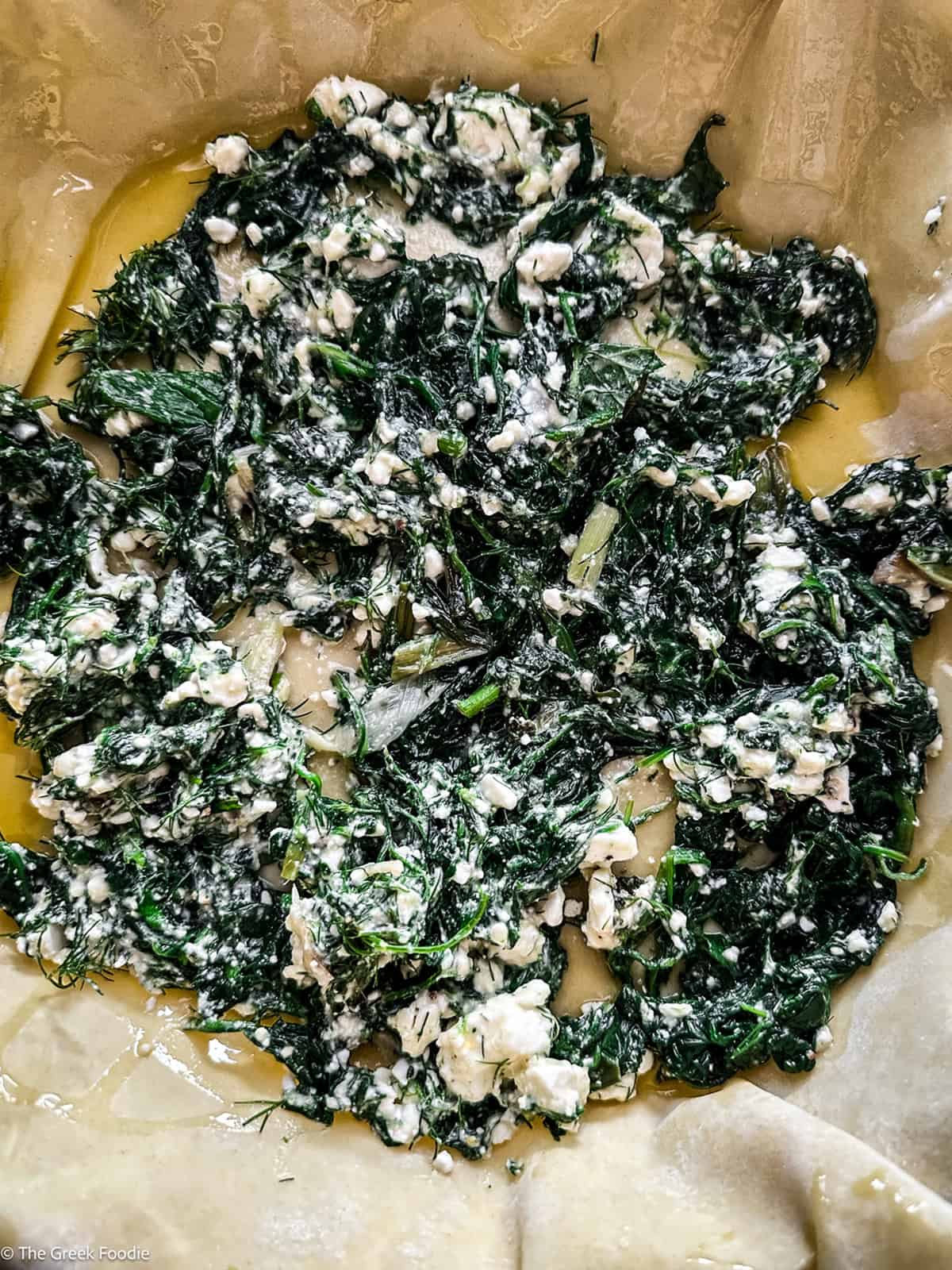 One-third of the spinach and feta filling spread over the phyllo in the baking pan.