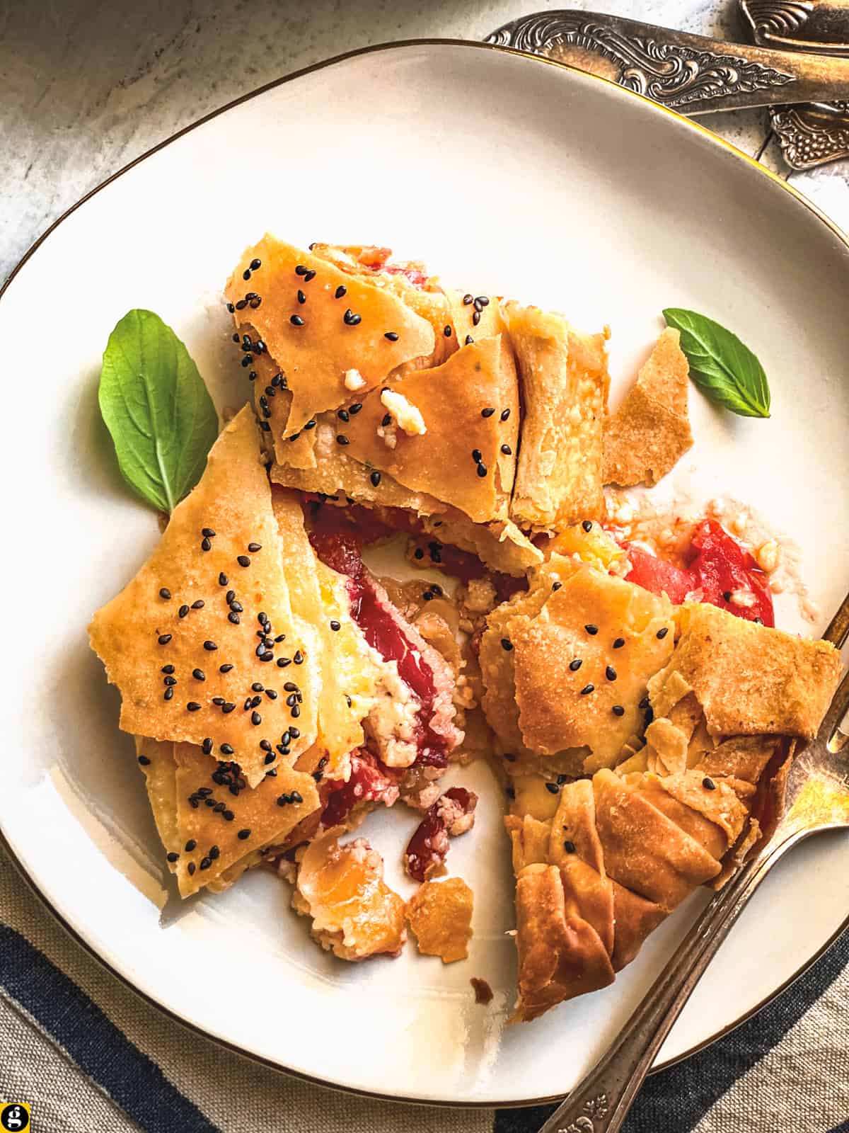 A plate of kasseri cheese pie pieces with melted cheese, pastirma and tomato