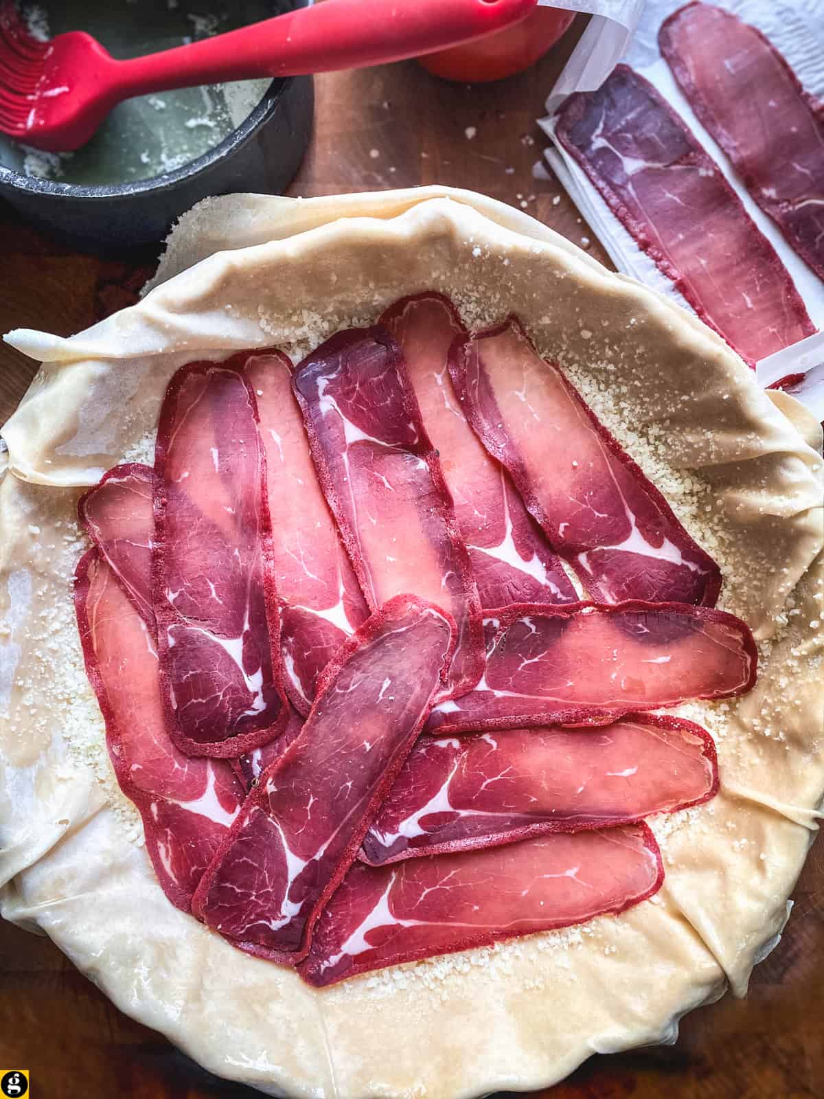 Slices of pastirma layered over phyllo in a tart pan