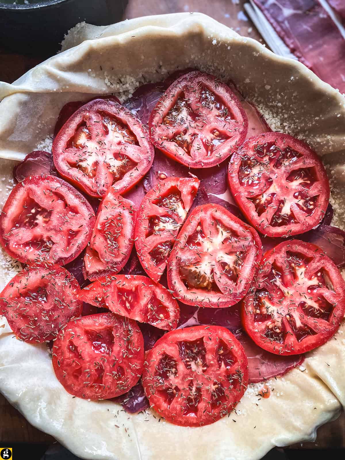 Thin tomato slices layered over pastirma in a phyllo-lined tart pan